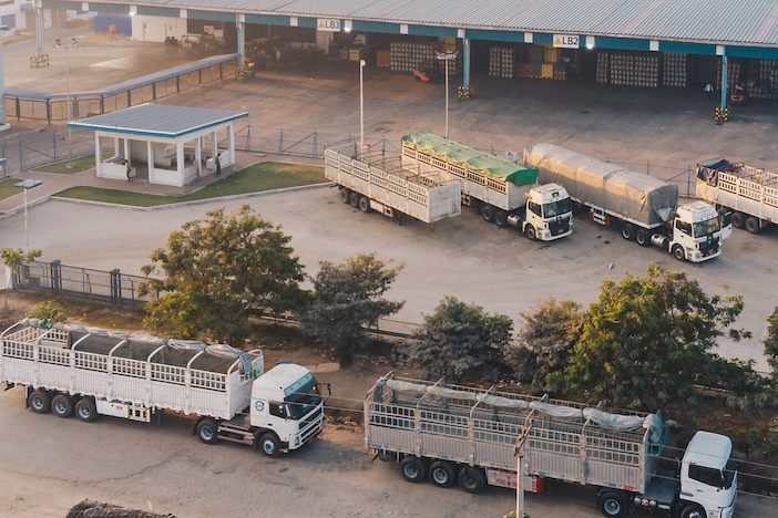 An aerial shot of factory trucks parked near the warehouse at daytime